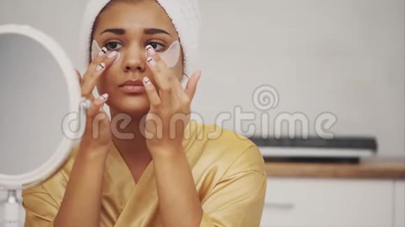 美丽女人沐浴后的特写肖像头上有毛巾眼睛下面有皱纹和深色的补丁视频的预览图