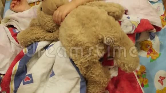 可爱的宝宝和一只玩具熊睡在小床上视频的预览图