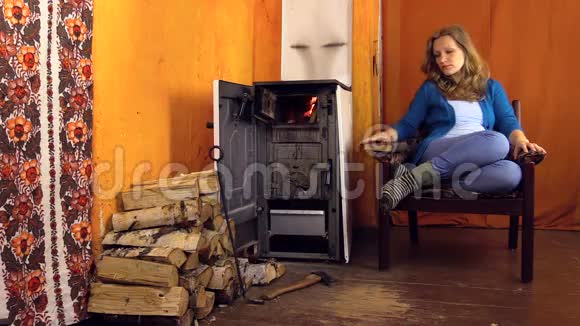有魅力的女人在扶手椅上放松在火炉边看书视频的预览图