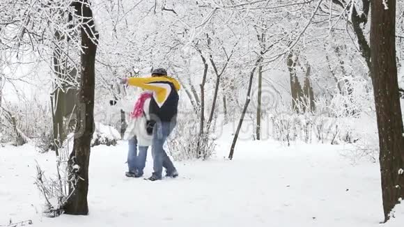 年轻夫妇在冬天的树林里散步视频的预览图