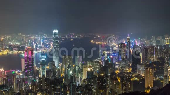 香港城市的天际线在夜晚随着维多利亚港和摩天大楼在水中的灯光照亮视频的预览图