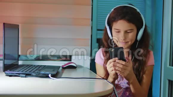 小女孩在智能手机上耳机听音乐青少年女孩在社交中翻阅播放列表音乐视频的预览图
