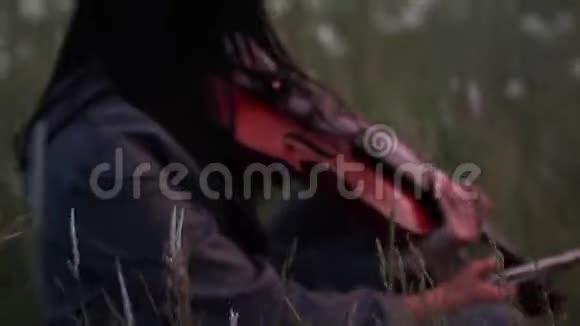 黄昏时分女小提琴手在草地上拉小提琴视频的预览图