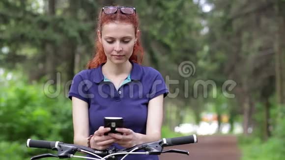 女孩坐在自行车上在智能手机上发短信视频的预览图