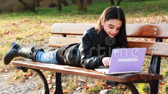 带着笔记本电脑坐在长凳上的青少年视频的预览图