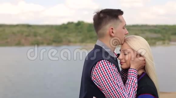 快乐的一对拥抱在湖的背景上视频的预览图