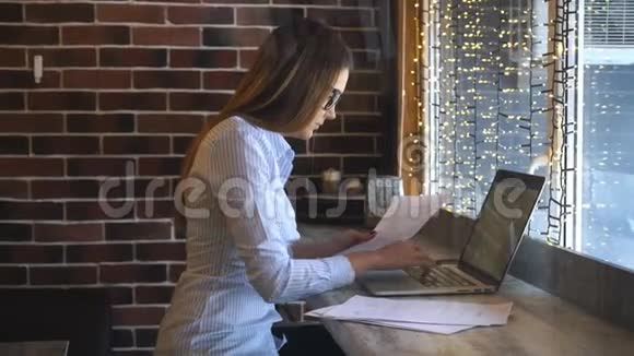 快乐的女人在咖啡馆用笔记本电脑年轻漂亮的女孩坐在咖啡店里用电脑工作视频的预览图