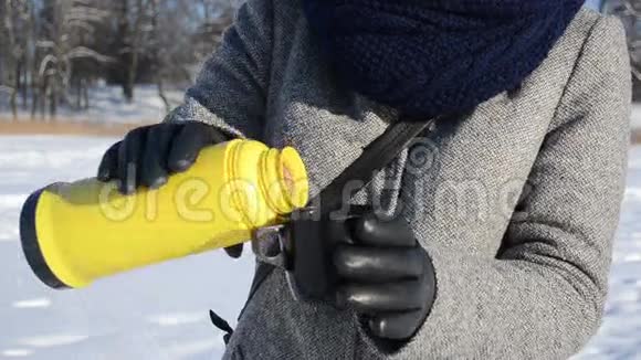 双手皮手套热茶黄热水瓶冬天视频的预览图
