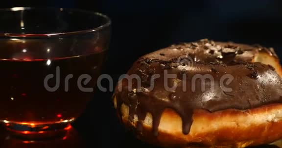 一杯黑色背景的茶和巧克力甜甜圈视频的预览图