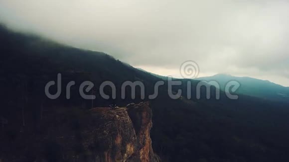 雾中站在山上的山地自行车运动员的史诗般的鸟瞰图多云的天空秋天的季节视频的预览图