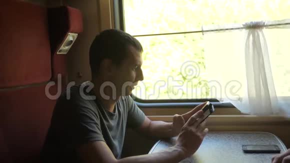 男人旅行者在火车上放松听音乐通过社交媒体微笑慢速视频视频的预览图