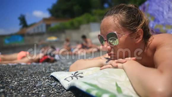 女人在沙滩上躺在石头上晒日光浴视频的预览图