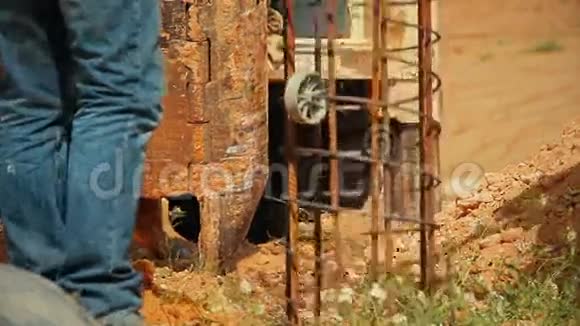 拖拉机举起一根钢棒把它放在地上的一个洞里建筑工人正在帮助他视频的预览图