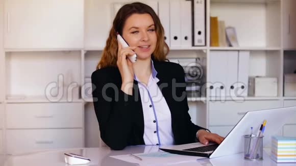 年轻而微笑的女办公室工作人员在打电话视频的预览图