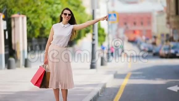 带着购物袋的年轻快乐的女孩坐出租车站在大街上举着一个美丽幸福的女人的肖像视频的预览图