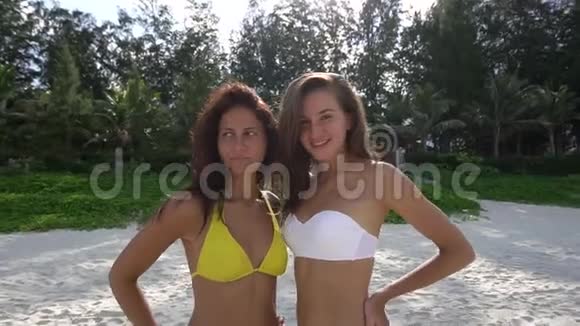 两个年轻漂亮的女孩在海滩上摆姿势拍照视频的预览图