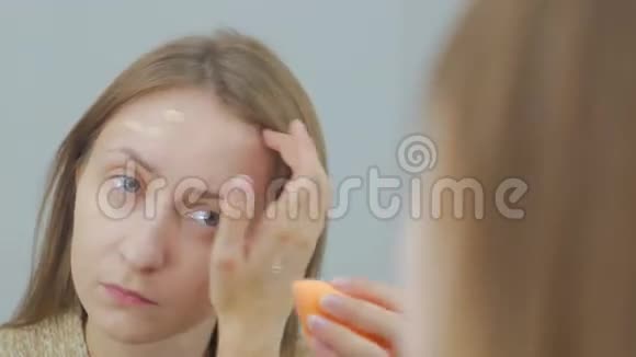 美丽的年轻女人用遮瑕霜化妆视频的预览图