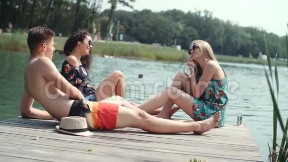 三个快乐的朋友在湖边放松视频的预览图