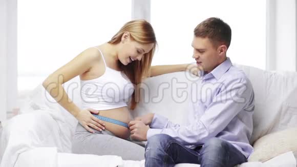 幸福的丈夫测量怀孕的妻子的腰围视频的预览图