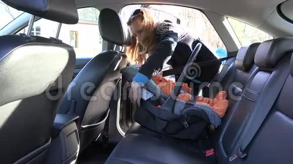 女人用皮带把婴儿安全椅固定在后座上4K视频的预览图