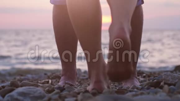 在美丽的夕阳下一对情侣在海边约会时的腿男人举起手来视频的预览图