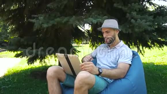 乔昆德的乐趣坐在包椅和支持最喜欢的运动团队在直播流与笔记本电脑视频的预览图