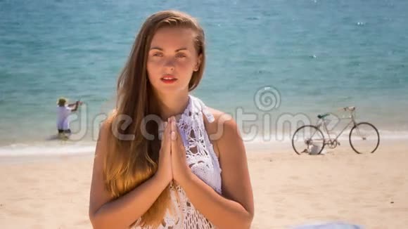 穿花边的金发女孩在海滩上练习瑜伽视频的预览图