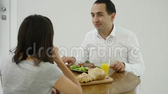快乐的一对夫妻在厨房里一起聊天和吃早餐视频的预览图