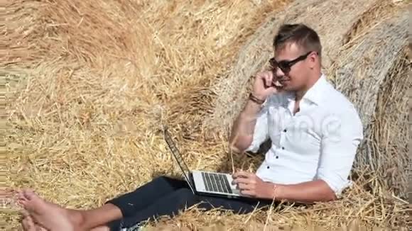 商人看起来很漂亮拿着笔记本电脑坐在干草堆里打电话暑假期间视频的预览图