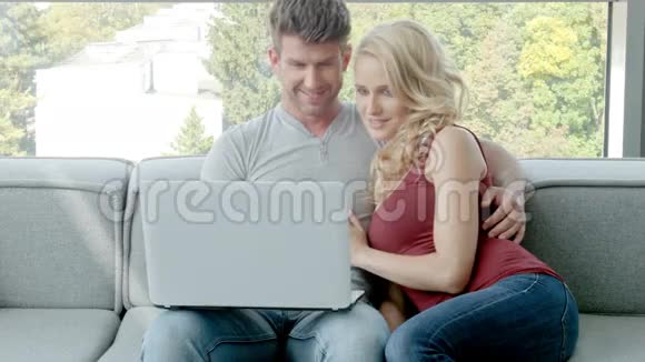 年轻夫妇用手提电脑坐在沙发上视频的预览图
