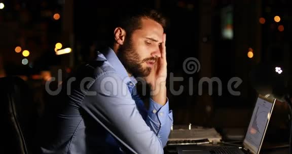 疲倦的商人晚上用笔记本电脑视频的预览图