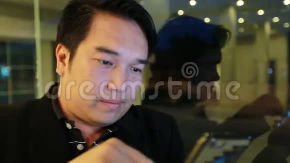 亚洲商人在咖啡馆晚上使用手机和智能手机帅哥在等人视频的预览图