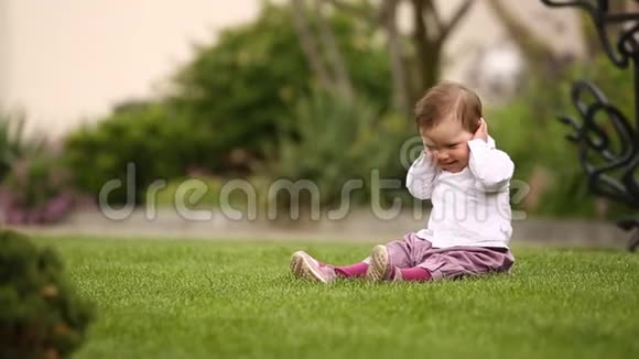 在城市公园的草地上坐着一个漂亮的小女孩视频的预览图