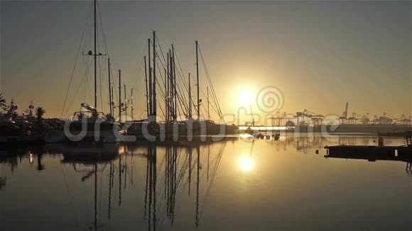 瓦伦西亚港的日出太阳从停靠的帆船和货船之间升起视频的预览图
