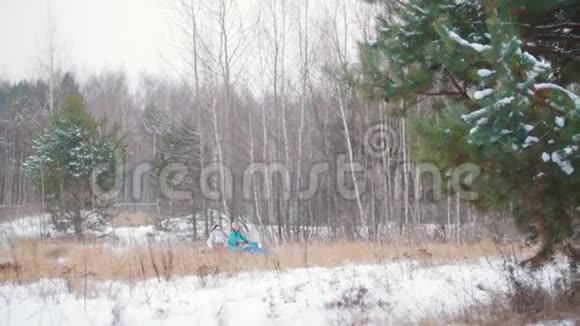在冬天的森林里乘雪车的年轻人视频的预览图