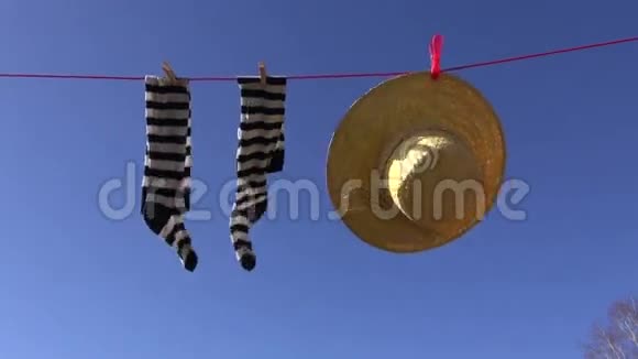 女式袜子和夏季草帽在蓝天上迎风洗衣服视频的预览图