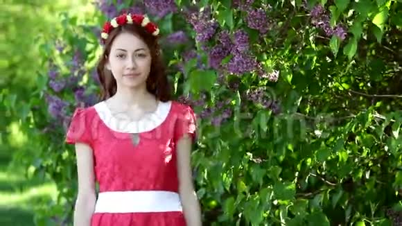 一位穿着红裙子的美女在公园里的丁香花间散步视频的预览图