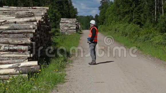 Lumberjack在智能手机上聊天在一堆木头附近散步视频的预览图