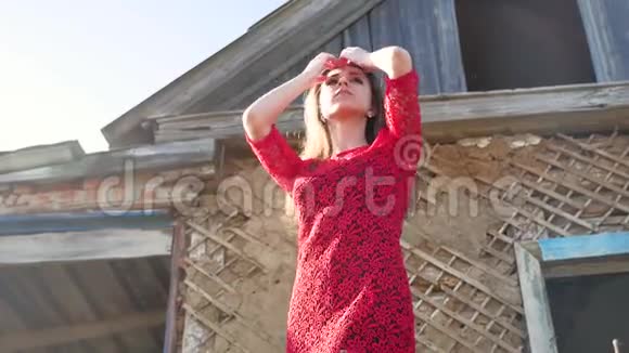 漂亮的生活方式女孩穿着红色连衣裙穿裙子的女孩站在废墟的老房子旁边视频的预览图