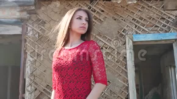 穿着红色裙子的漂亮女孩的生活方式穿裙子的女孩站在废墟的老房子旁边视频的预览图