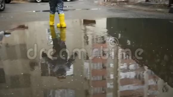 雨后小男孩走过春天的水坑视频的预览图