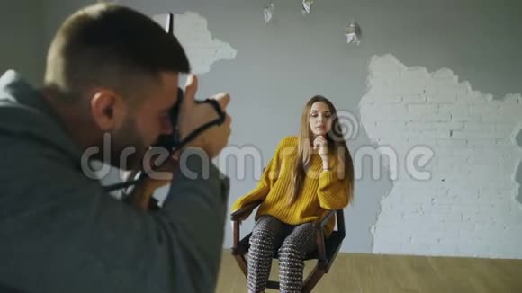 年轻漂亮的女模特在室内照相馆用数码相机拍照时为摄影师摆姿势视频的预览图