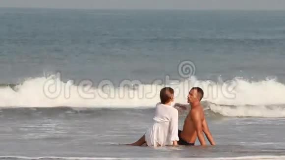 年轻夫妇坐在海边沙滩上视频的预览图