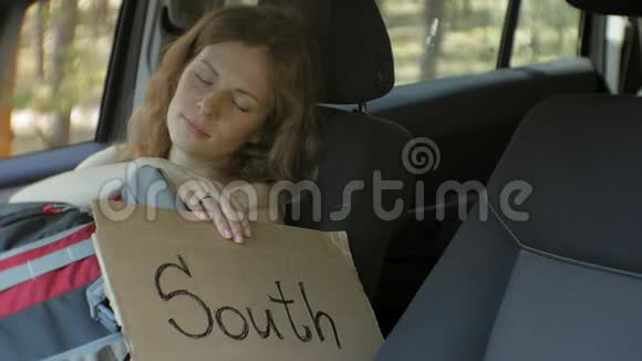年轻漂亮的女人搭车站在路上背包放在桌子上桌上写着南方的字样视频的预览图