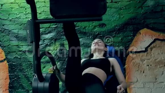 一个有魅力的女人在运动健身房的模拟器上做伸展运动视频的预览图