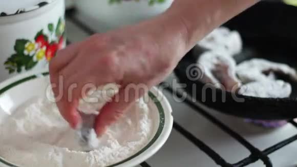 一个女人把一条鲜鱼裹在面粉里放进煎锅里视频的预览图