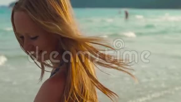慢镜头拍摄一个年轻的暴跳如雷的女人在海滩和海里玩视频的预览图