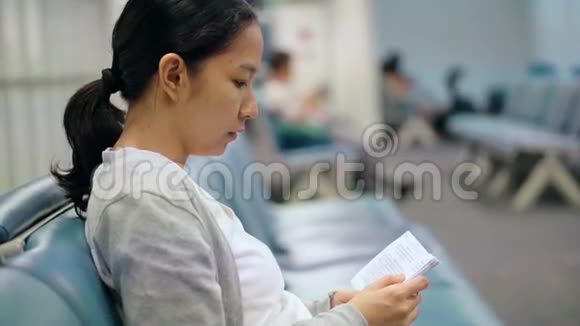 美丽的亚洲女子读本机场候机室视频的预览图
