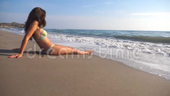 穿比基尼的年轻女孩躺在海边和日光浴无法辨认的女人在夏天在海边放松视频的预览图