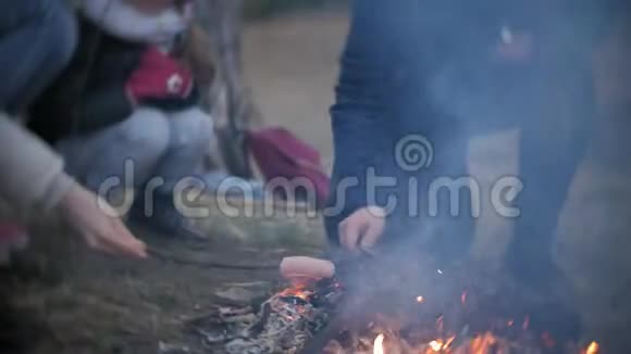 旅途中游客的幸福家庭妈妈和孩子们在帐篷附近的火上煎香肠视频的预览图